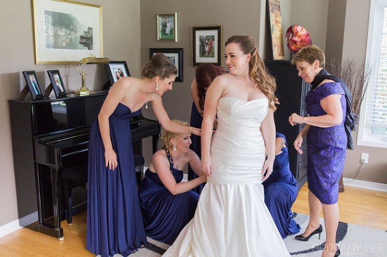 Bride getting dressed with bridesmaids before ceremony 
