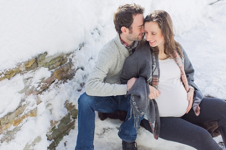 Mont Tremblant Winter Maternity Photos - pregnant couple sitting on snowy ledge with blanket