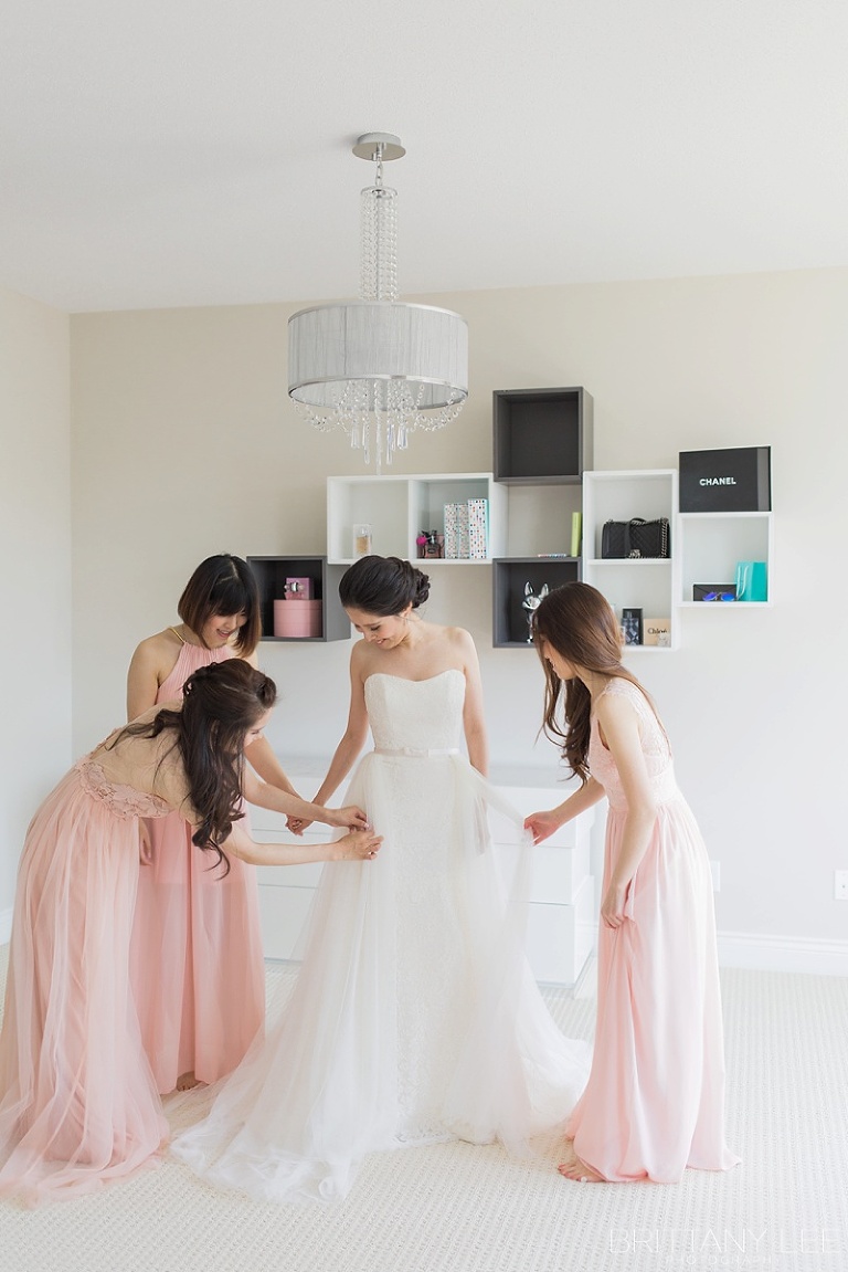 Bridesmaids helping bride into dress