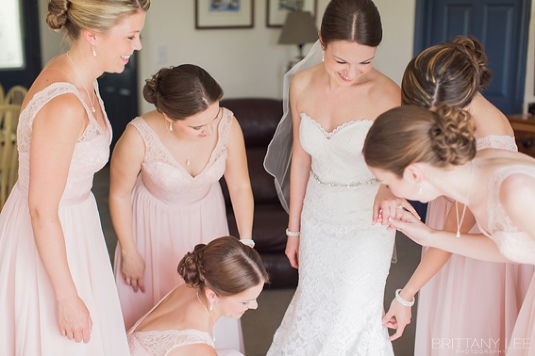 Bridesmaids helping bride into her wedding dress at Strathmere Ottawa
