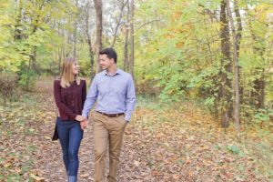 Stonebridge Trail Fall Engagement Session - Bride and Groom on walking along pathway with fallen leaves